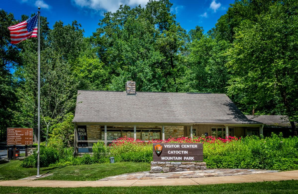 A stone and wood building with plants and flowers in front